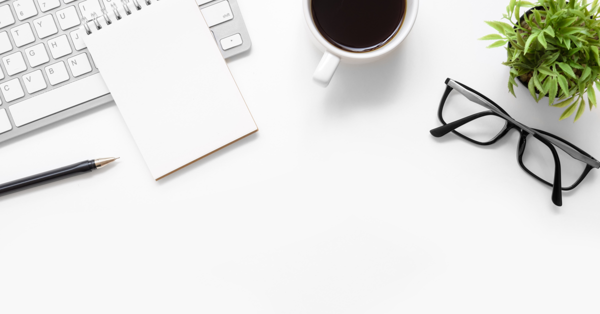 White office desk table with blank notebook, computer keyboard and other office supplies