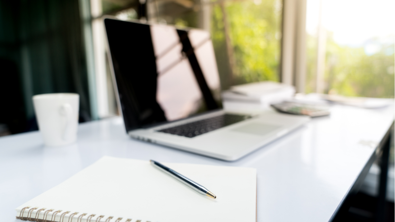 Top view desk of work table in office with laptop computer, notebook, calculator and a cup of coffee