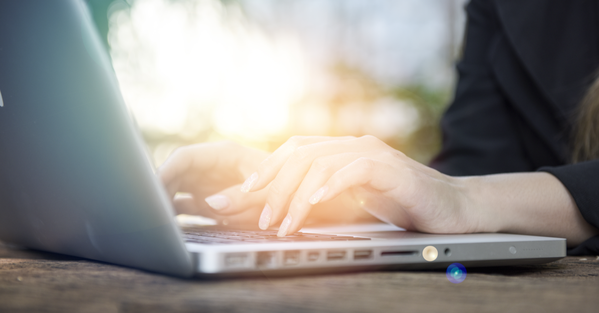 Woman’s hands typing on silver laptop computer on desk
